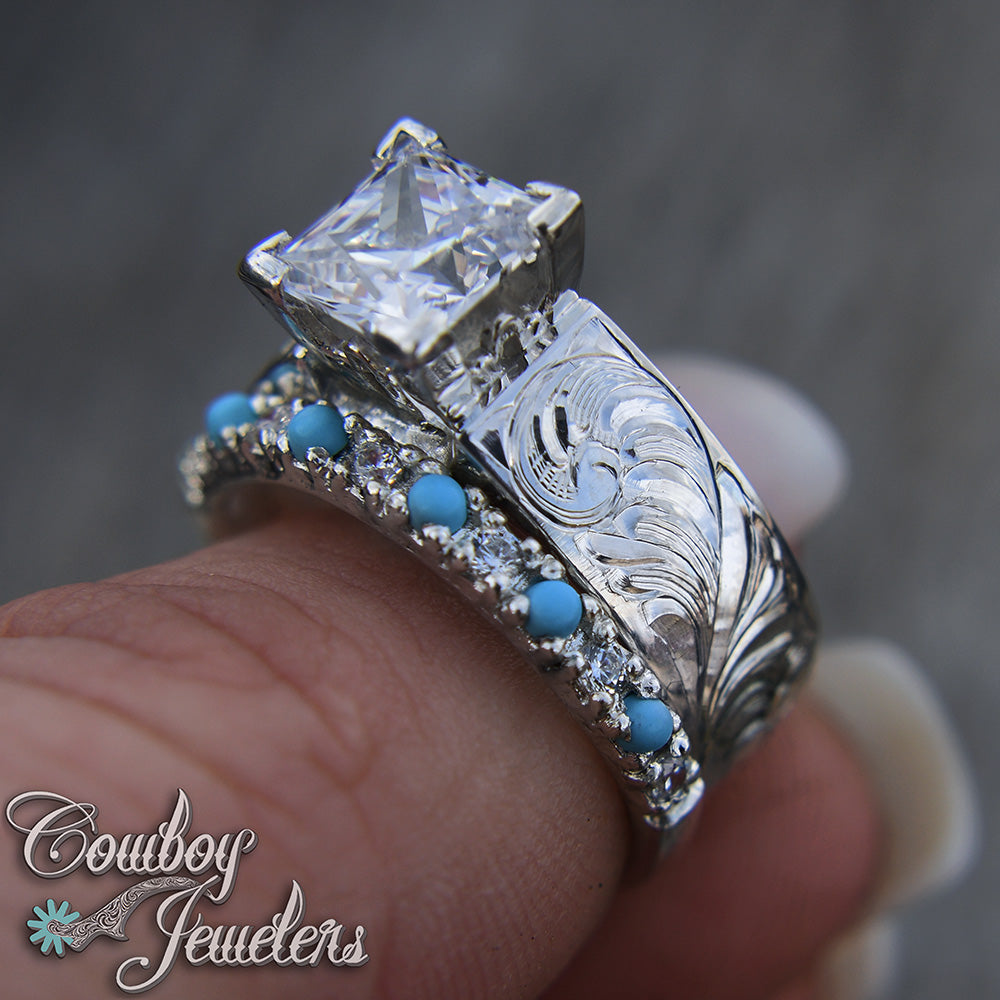 Silver ring with turquoise stones and engraving design on a finger, branded 'Cowboy Jewelers'