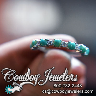 Turquoise ring held by a hand with 'Cowboy Jewelers' branding and contact information.
