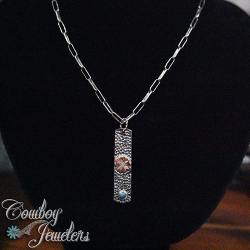 Silver necklace with a flower and turquoise pendant on a black background, featuring 'Cowboy Jewelers' branding.