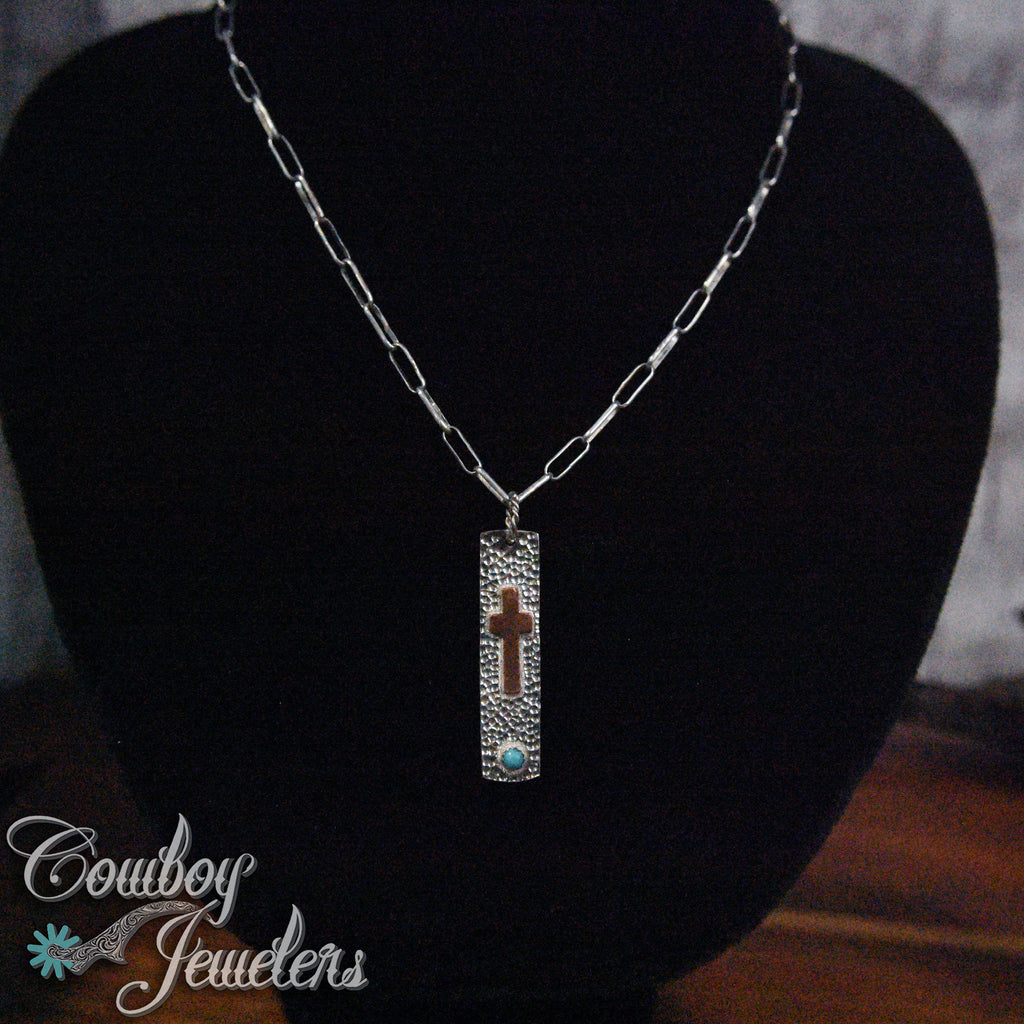 Necklace silver and copper with a pendant on a black stand, branded 'Cowboy Jewelers'.