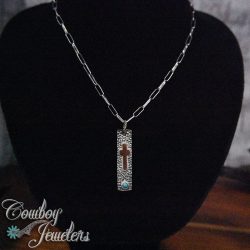 Necklace silver and copper with a pendant on a black stand, branded 'Cowboy Jewelers'.
