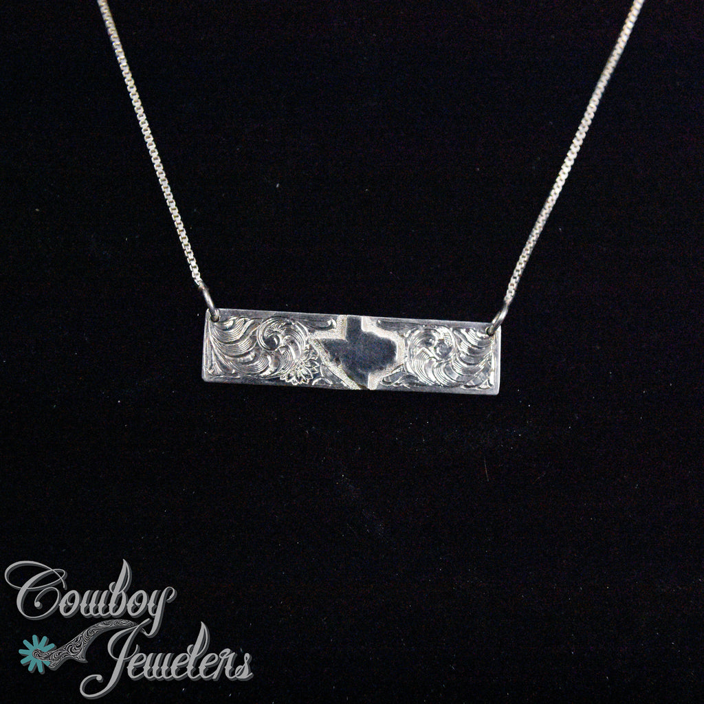 Silver necklace with a Texas state emblem  on a black background, branded 'Cowboy Jewelers'.