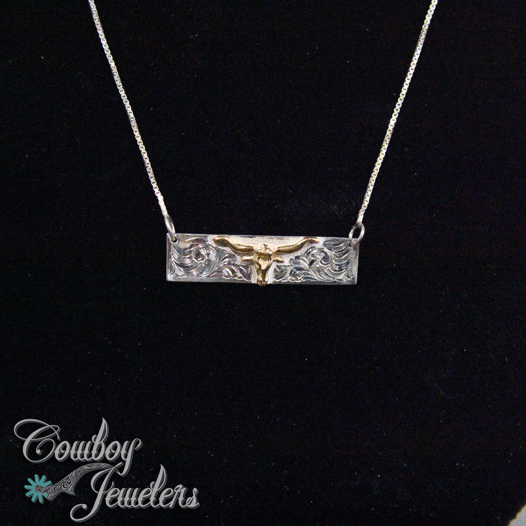 Silver and gold longhorn bull necklace on a black background with 'Cowboy Jewelers' branding.