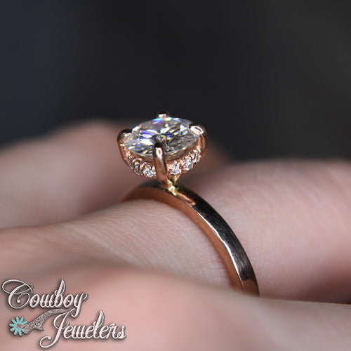 Rose gold ring with a large diamond on a hand, branded 'Cowboy Jewelers'.