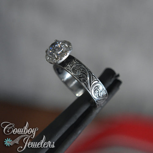 Engraved Silver ring with diamond on a blurred background, featuring 'Cowboy Jewelers' branding.