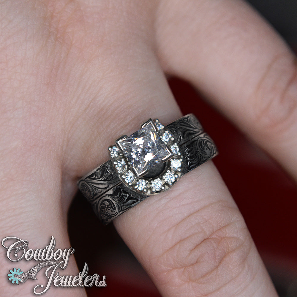 Engraved horseshoe  ring with a prominent diamond on a finger, branded 'Cowboy Jewelers'.