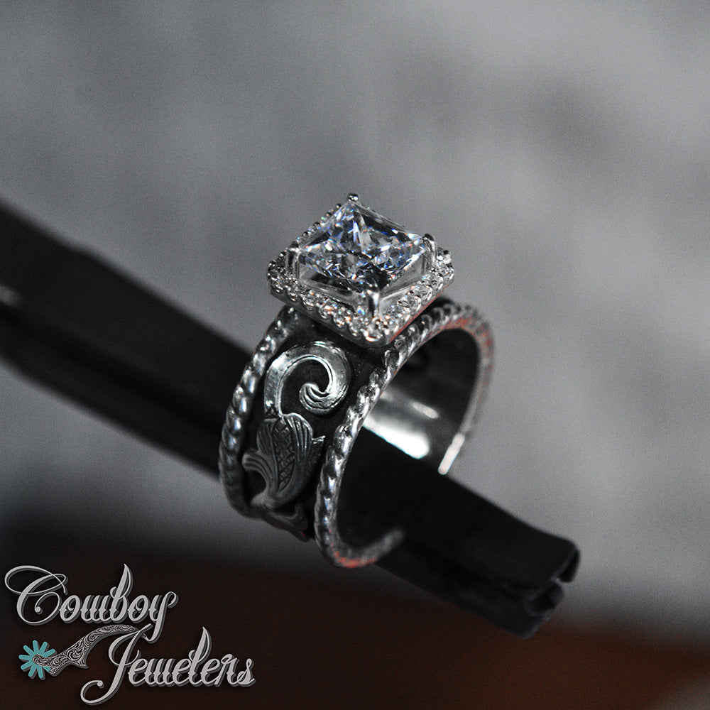 Diamond ring with halo setting  intricate design on a dark background, featuring 'Cowboy Jewelers' logo.