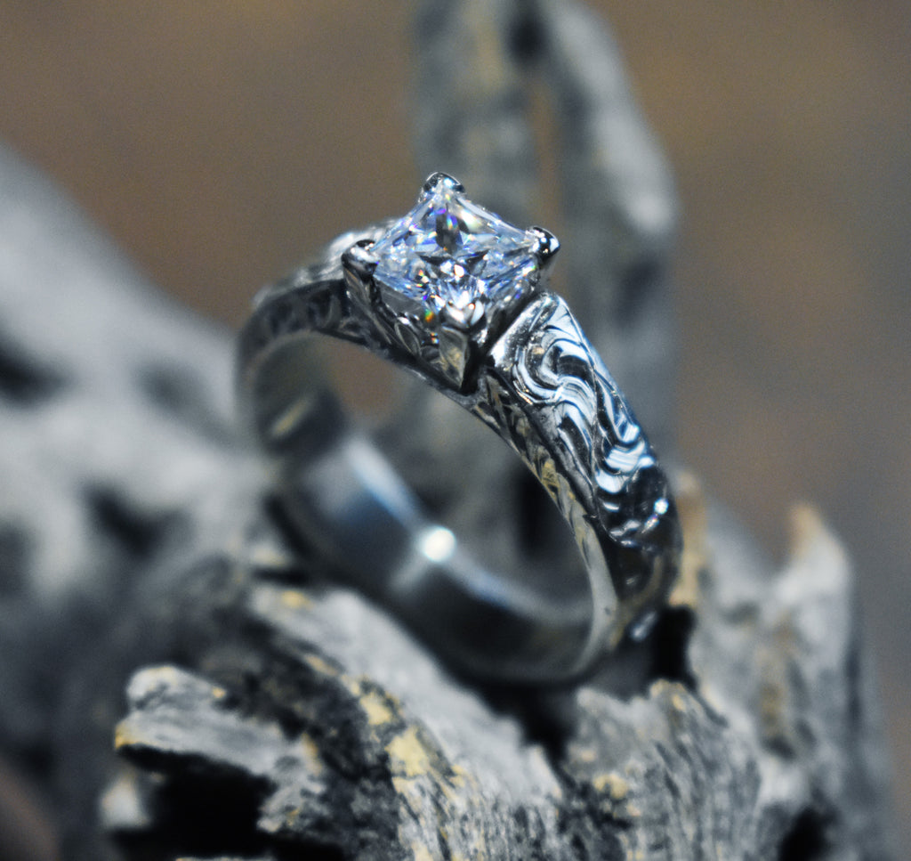 Silver engraved ring with a diamond on a textured surface