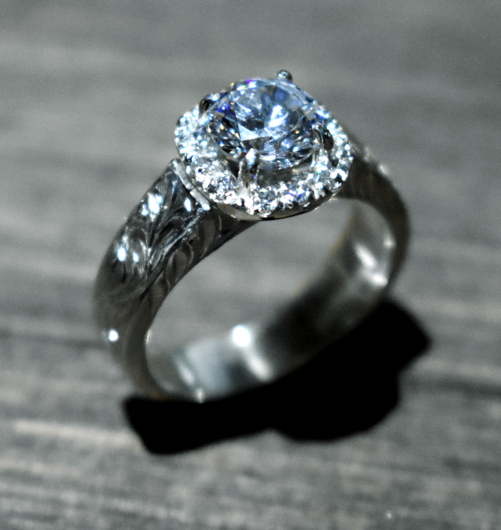 Silver engraved ring with a large diamond on a textured gray surface