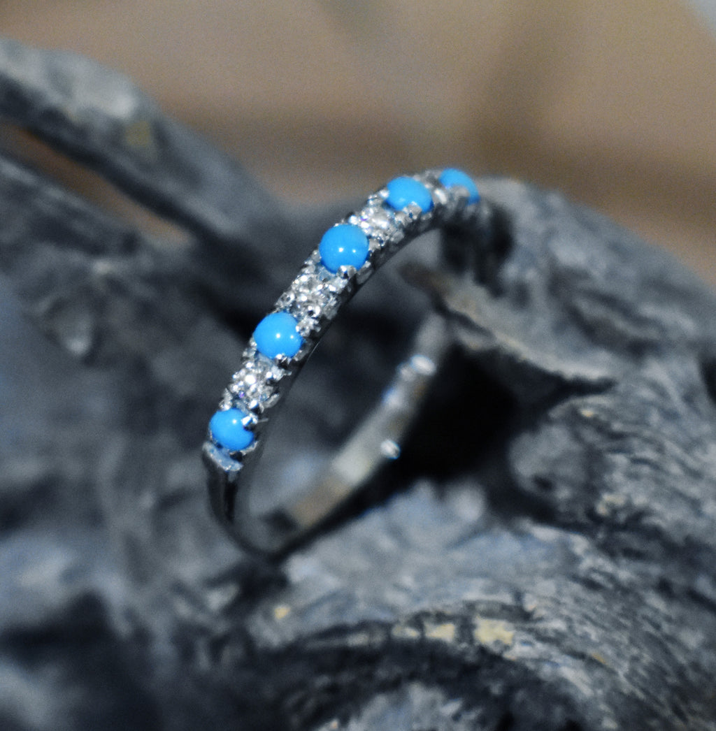 Ring with blue turquoise stones and diamond stones on a dark surface